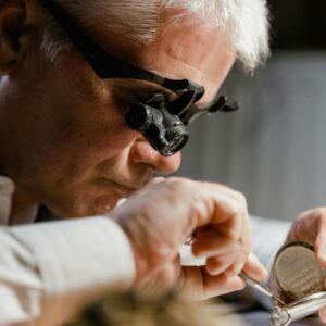 Watchmaker in action repairing a clock with precision tools in workshop setting.